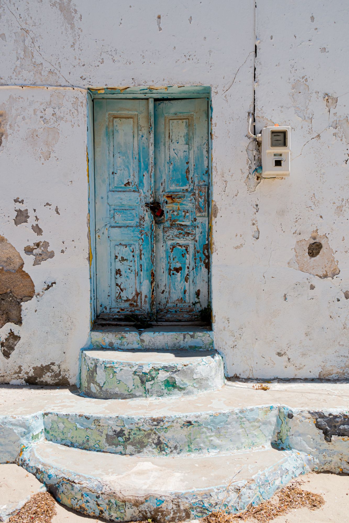 A weathered blue door in a whitewashed wall